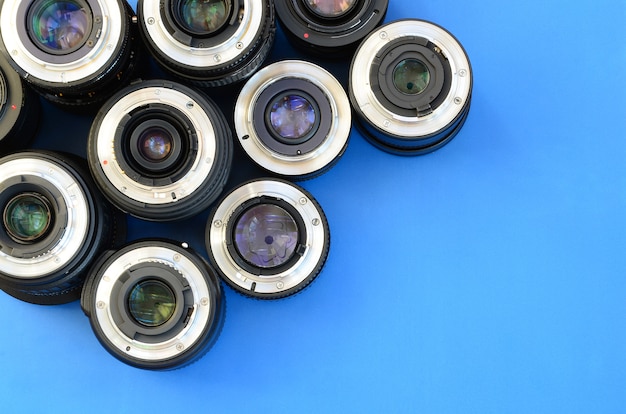 Several photographic lenses lie on a bright blue background. Space for text