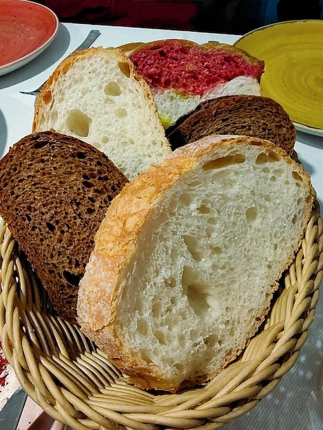 Several pieces of bread of different colors and composition lie in a wicker basket for food