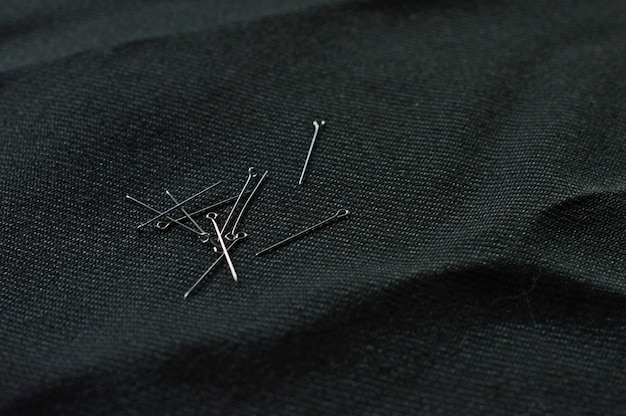 Several pins are scattered on the black cloth. close-up.