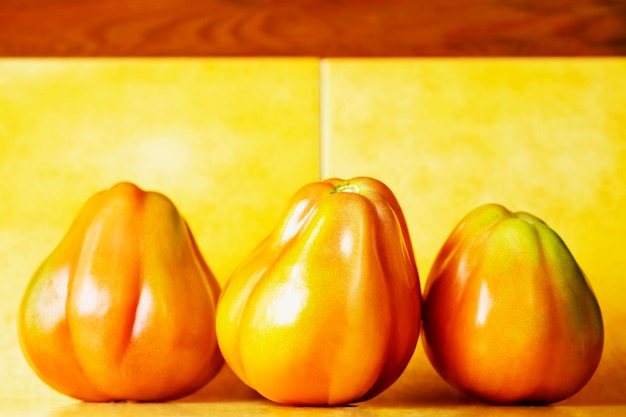 Photo several red beef tomates on colored background  bright and vivid colors  studio shot