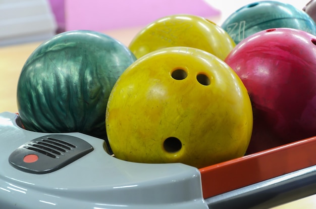Фото Несколько потрепанных шаров для боулинга разного цвета и веса на подставке