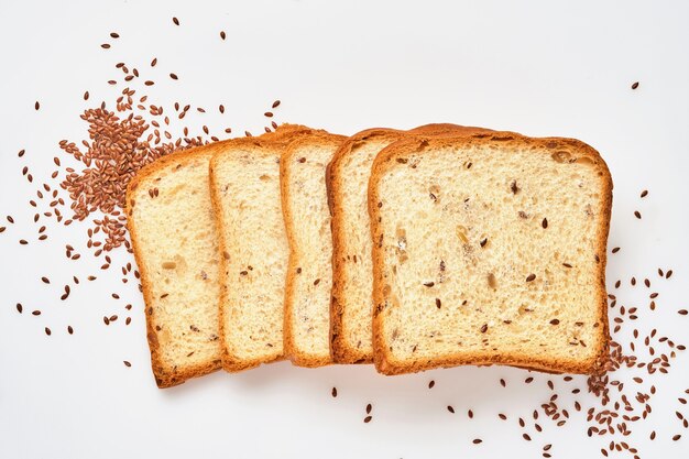 Several slices toast bread with pumpkin, poppy, flax, sunflower, sesame and millet seeds  isolated on white background for proper nutrition. Top view, flat lay