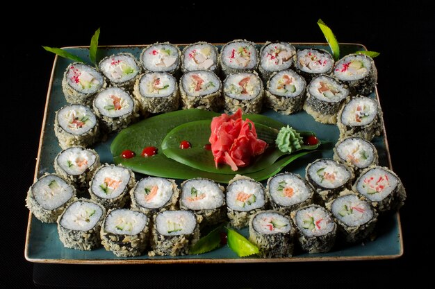 Several sushi laid out on a plate with ginger sauce wasabi Rolls from above