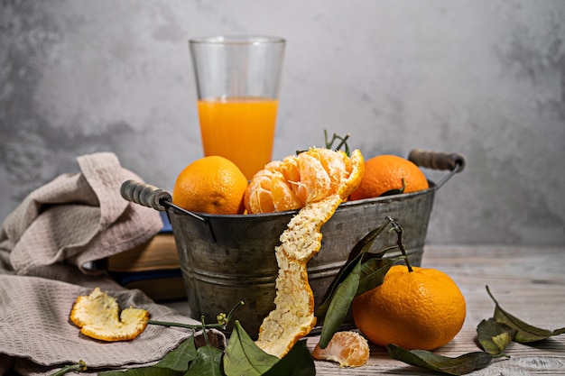 Several tangerines with leaves in a container lie on a white table