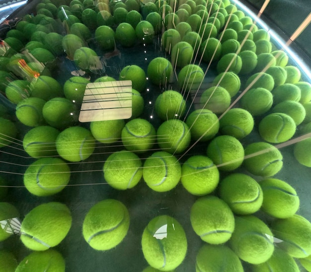 Several tennis balls behind a glass with light reflections green and gray background