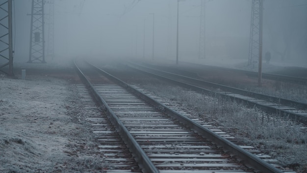 Несколько железнодорожных путей заканчиваются в тумане, железнодорожные пути холодным осенним утром