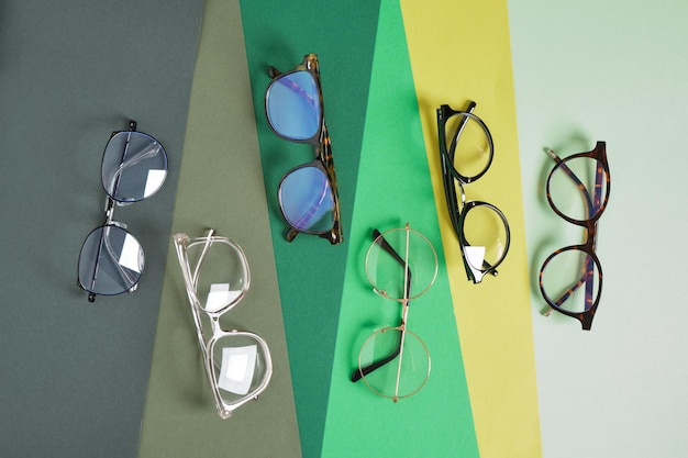 Several trendy stylish pairs of eye glasses on a geometric background of different shades of green