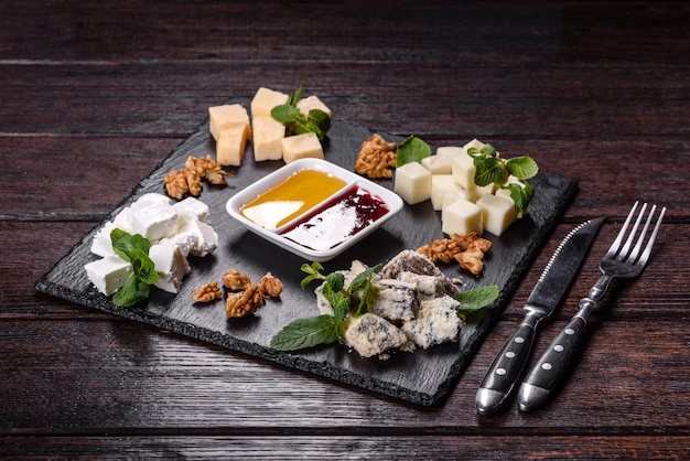 Several types of cheese on a shale tray with mint and sweet sauces