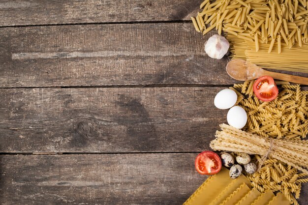 Several types of dry pasta with tomatoes.