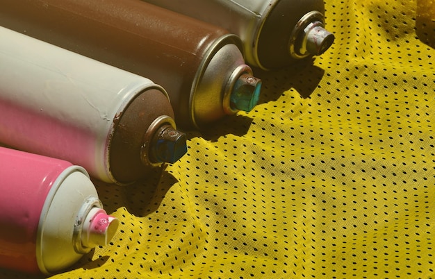 Several used aerosol paint sprayers lie on the sports shirt of a basketball player made of