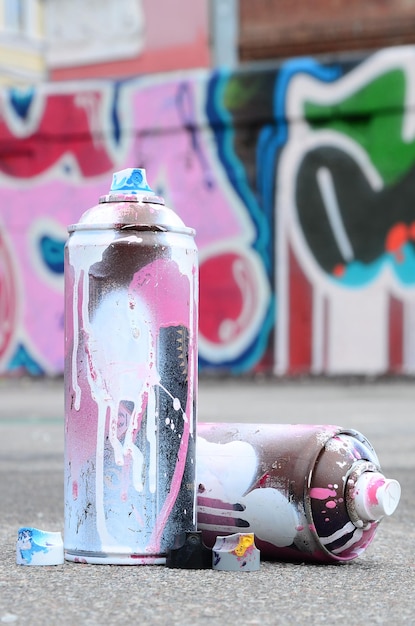 Фото several used spray cans with pink and white paint and caps for spraying paint under pressure is