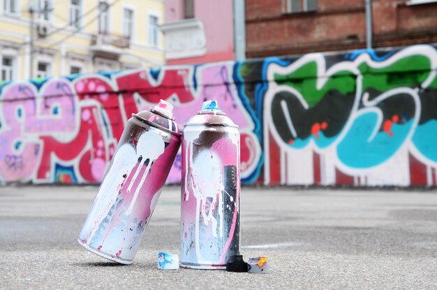 Photo several used spray cans with pink and white paint and caps for spraying paint under pressure is