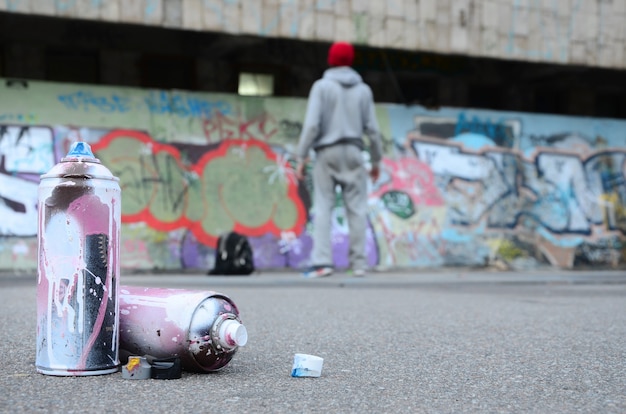 Several used spray cans with pink and white paint lie on the asphalt