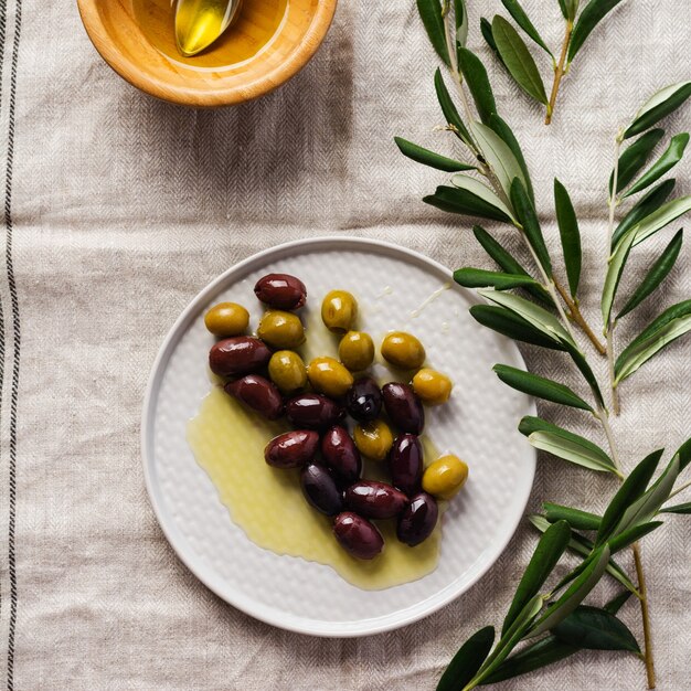 Several varieties of fresh olives in different ceramic plates on an old vintage gray napkin tablecloth. Natural product concept. Rustic vintage set of cutlery. Top view, copy space.