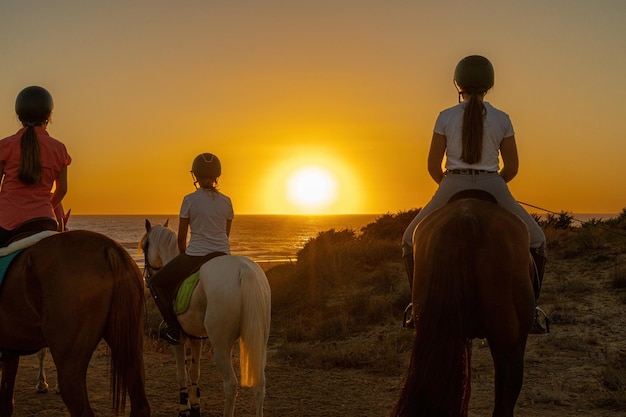 Several young riders watch the sunset on the sea above a hillside