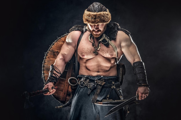 Severe barbarian in warrior clothes, posing on a dark background.