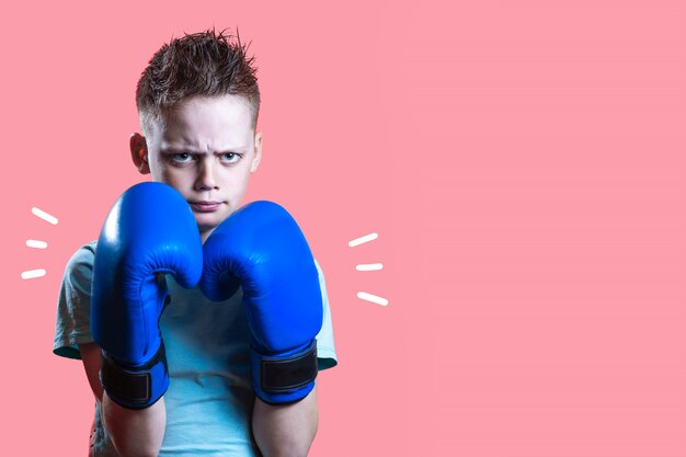 Severe boy in blue Boxing gloves on bright yellow