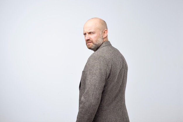 Severe strict man with beard in casual suit turning back