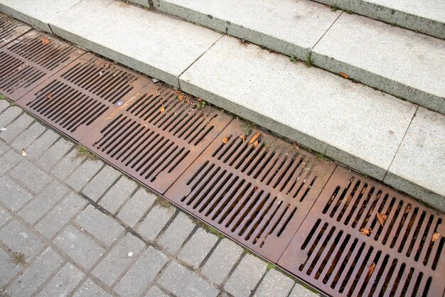 The sewer grate on the sidewalk is rusty