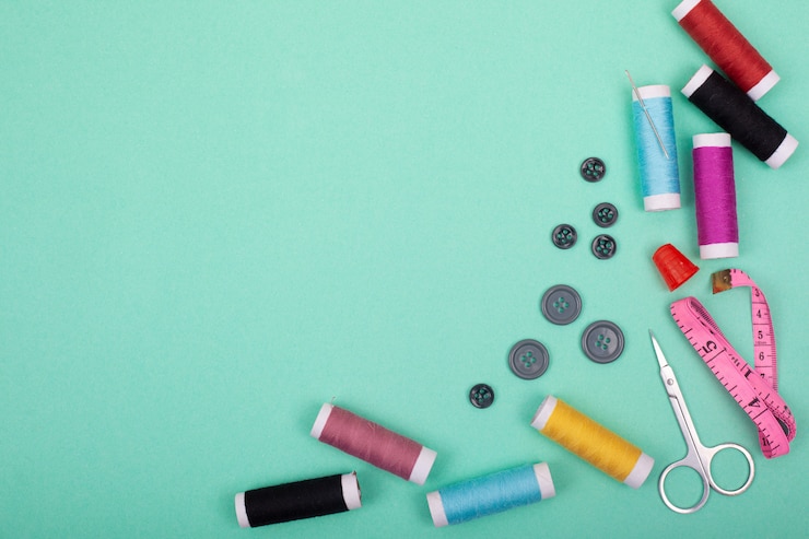 Photo sewing kit accessories.set tools for tailoring and colorful threads,needles,pins,scissors on green background mockup frame top view.