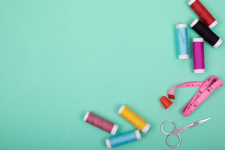 Photo sewing kit accessories.set tools for tailoring and colorful threads,needles,pins,scissors on mint background mockup frame top view.