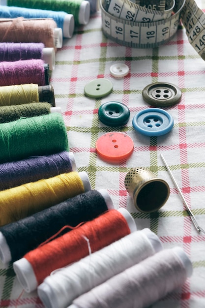 Sewing kit consisting needle thimble threads and measuring meter on a fabric background