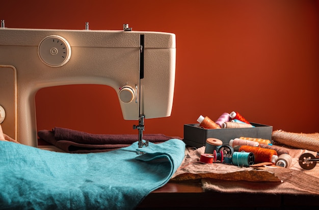 Фото Швейная машина и швейные принадлежности на коричневом фоне. концепция шитья.
