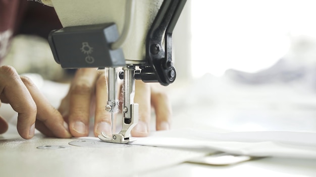 Sewing on machine close up of hands and white cloth