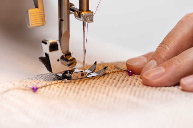 Photo sewing machine foot on fabric with needle and thread ready to sew the operators hand on the mater