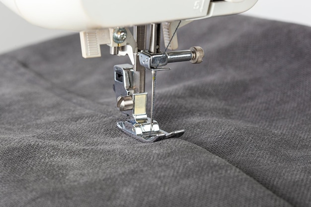 Швейная машина сшивает ткани иглой в круглом плане крупным планом