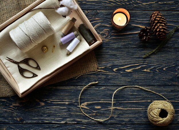 Sewing materials and burning candle on a dark wooden  Top view. Close-up. Flat lay.