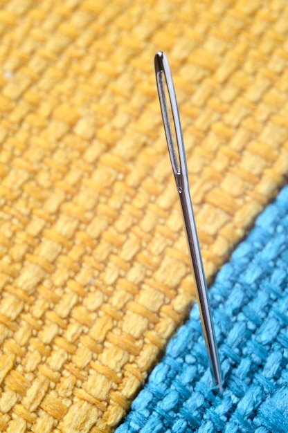 Sewing needle on a yellow fabric background. close-up.