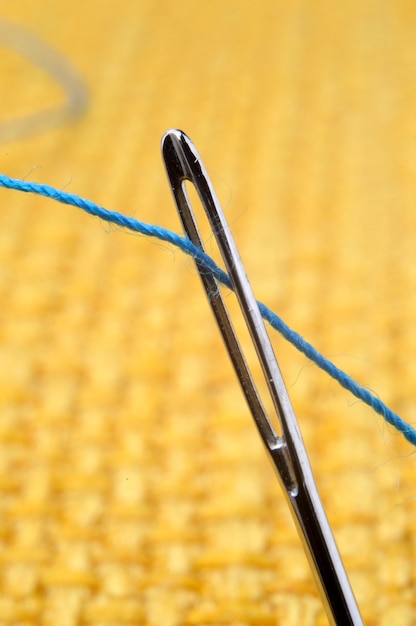 Photo sewing needle on a yellow fabric background closeup