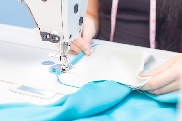 Sewing Studio. seamstress sewing on a sewing machine close-up. A set of items for needlework: threads, needles, pins, scissors, tape measure, etc.