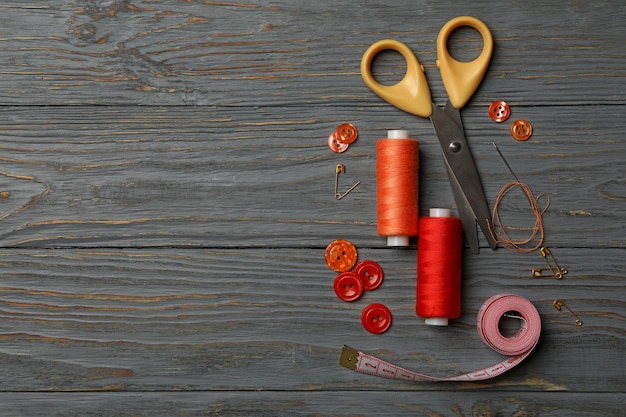 Sewing supplies on gray wooden background 