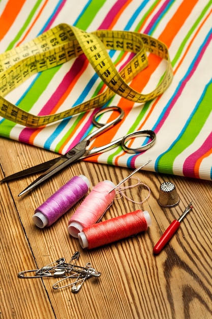 Photo sewing threads pools and scissors on a wooden table