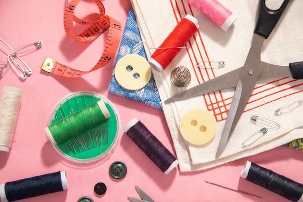 Sewing tools on the pink paper background