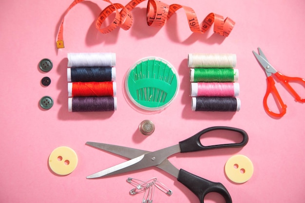ピンクの紙の背景に裁縫道具