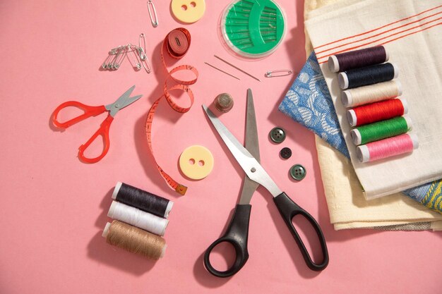 Sewing tools on the pink paper background