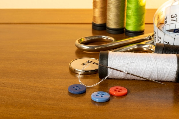 Sewing trims. spool of thread, needle, buttons, scissors and measuring tape.