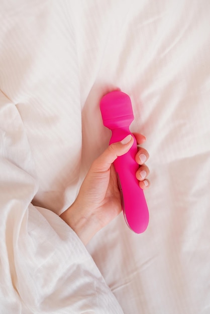 Sex toys Woman hand holding pink vibrator in bed