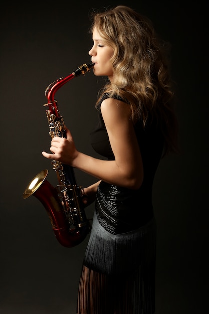 Sexy aantrekkelijk blondevrouwenmodel met saxofoon