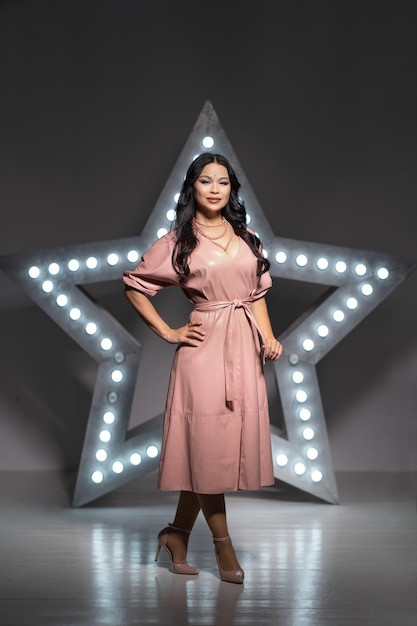 Sexy modella asiatica milf sta mezzo giro sullo sfondo di una stella gigante nel buio studio gi...