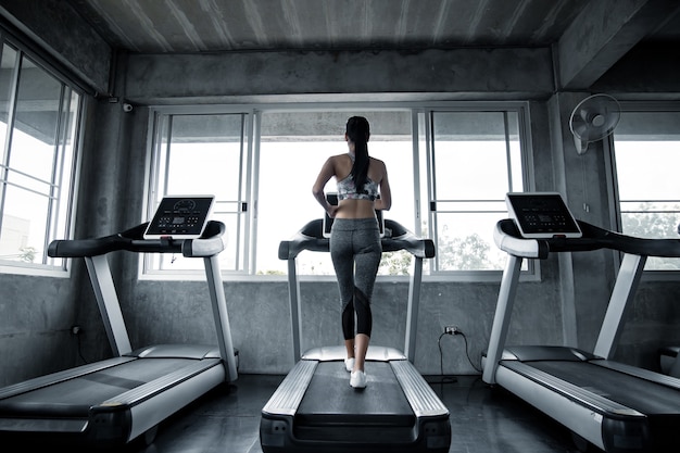 Donne asiatiche sexy che si esercitano sulla macchina da corsa in palestra. allenamento della donna in palestra sano. concetto di assistenza sanitaria con esercizio in palestra. bella ragazza che gioca fitness in palestra.