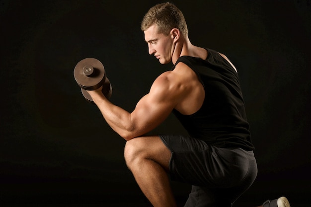 Sexy athlete with dumbbell on black background