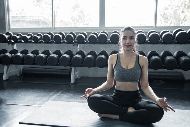 Sexy Aziatische vrouw die yoga speelt in de sportschool. Concept van oefening in de sportschool. Vrouw workout yoga op mat.