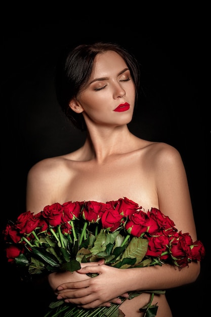 Sexy beautiful woman holding large bouquet of red roses