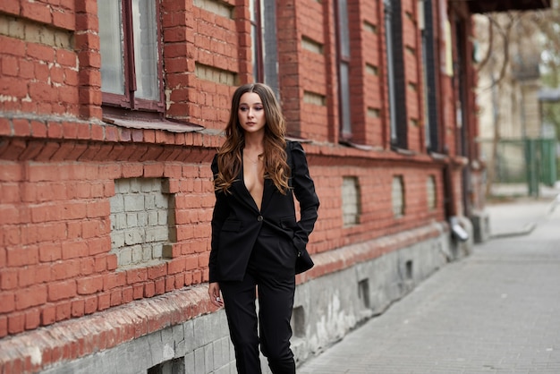 sexy Beautiful women. Fashionable girl in a black suit near the brick wall. womens streetwear 2020. street style woman. how to dress this spring 2020