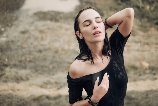 Sexy beautiful young woman enjoying summer rain attractive brunette woman wearing black bodysuit and...