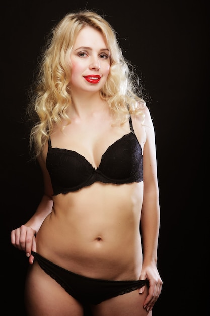 Sexy blond woman with curly hair in black lingerie